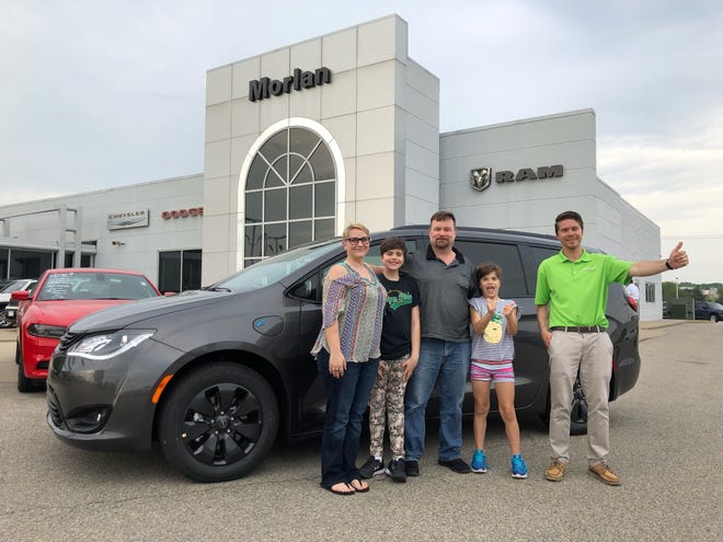 The Salina, Kansas, family of (l-r) Sarah Spurlock, Juliahna Brown, Joel Spurlock and Jillian Brown pose with sales person Wes Adelman in front of the Chrysler Pacifica plug-in hybrid electric vehicle they bought from Morlan Chrysler Dodge Jeep Ram in Cape Girardeau, Missouri.
