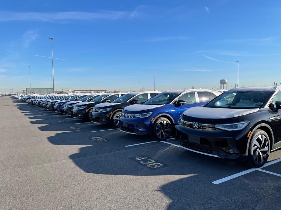 Dozens of VW ID.4 EVs lined up in parking lot.