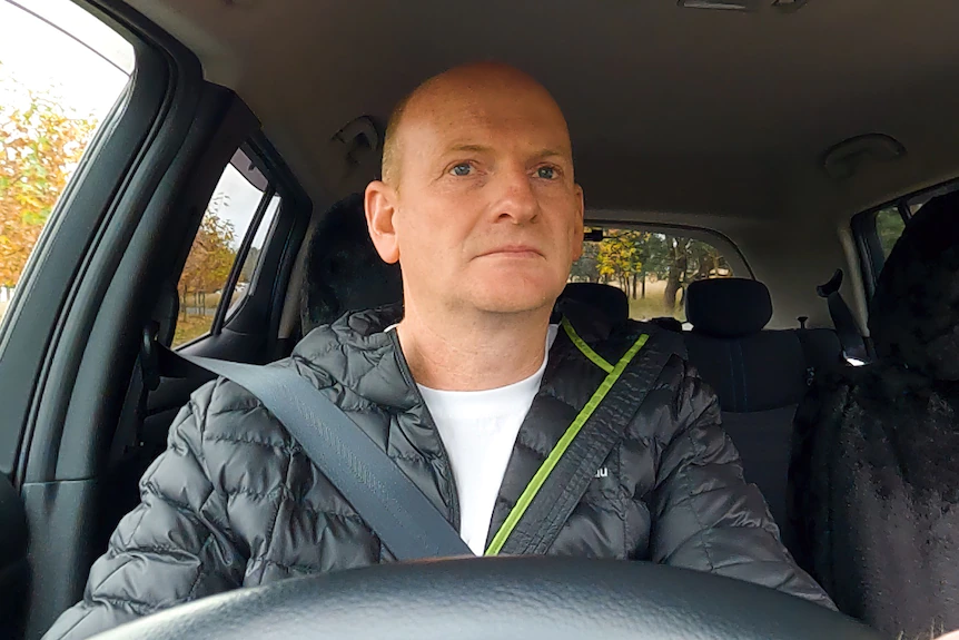 Shane sitting in the driver seat of his car holding the steering wheel