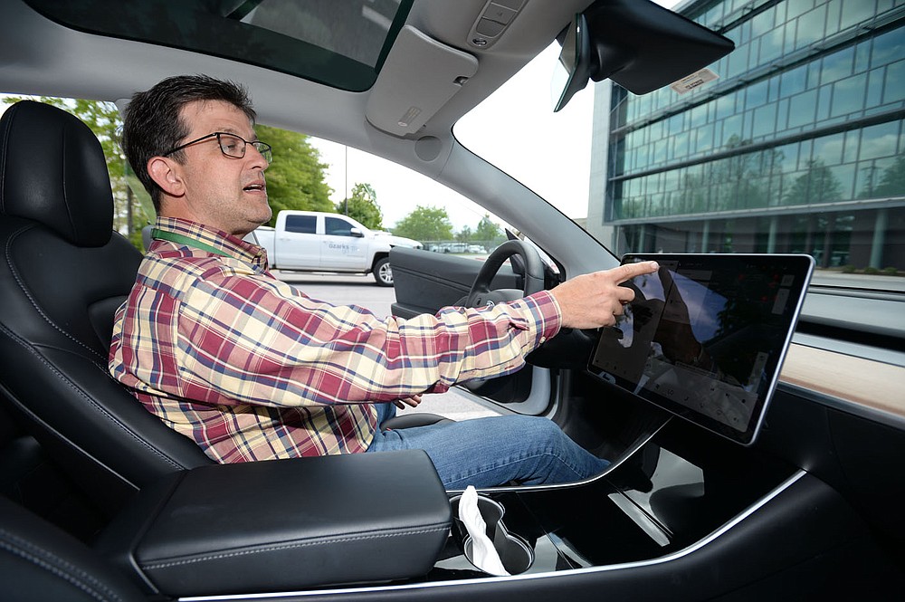 Kris Williams, director of energy services for Ozarks Electric Cooperative Corp. demonstrates the navigation system of the cooperative√çs Tesla Model 3 electric vehicles assists in planning a route to a destination with consideration of where charging stations are located Wednesday, May 12, 2021, at the cooperative√çs offices in Fayetteville. It can be challenging to find charging stations for electric vehicles in rural areas of Arkansas, but both the state and private companies are working to change that. Visit nwaonline.com/210518Daily/ for today's photo gallery. 
(NWA Democrat-Gazette/Andy Shupe)
