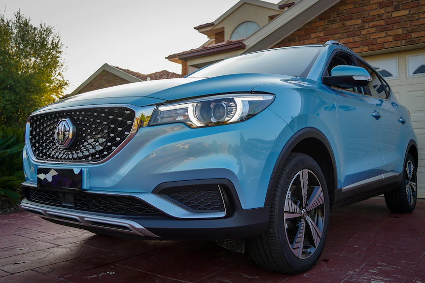 A blue SUV sits in a suburban driveway