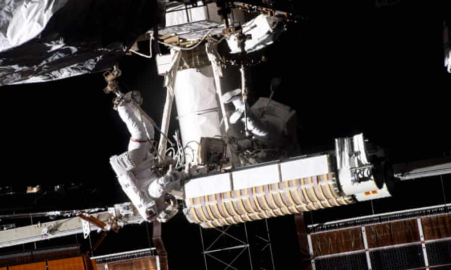 Thomas Pesquet (L) of the European Space Agency is attached to an articulating portable foot restraint on the end of the Canadarm2 robotic arm carrying new roll out solar arrays towards the International Space Station’s P-6 truss structure, next to US astronaut Shane Kimbrough.