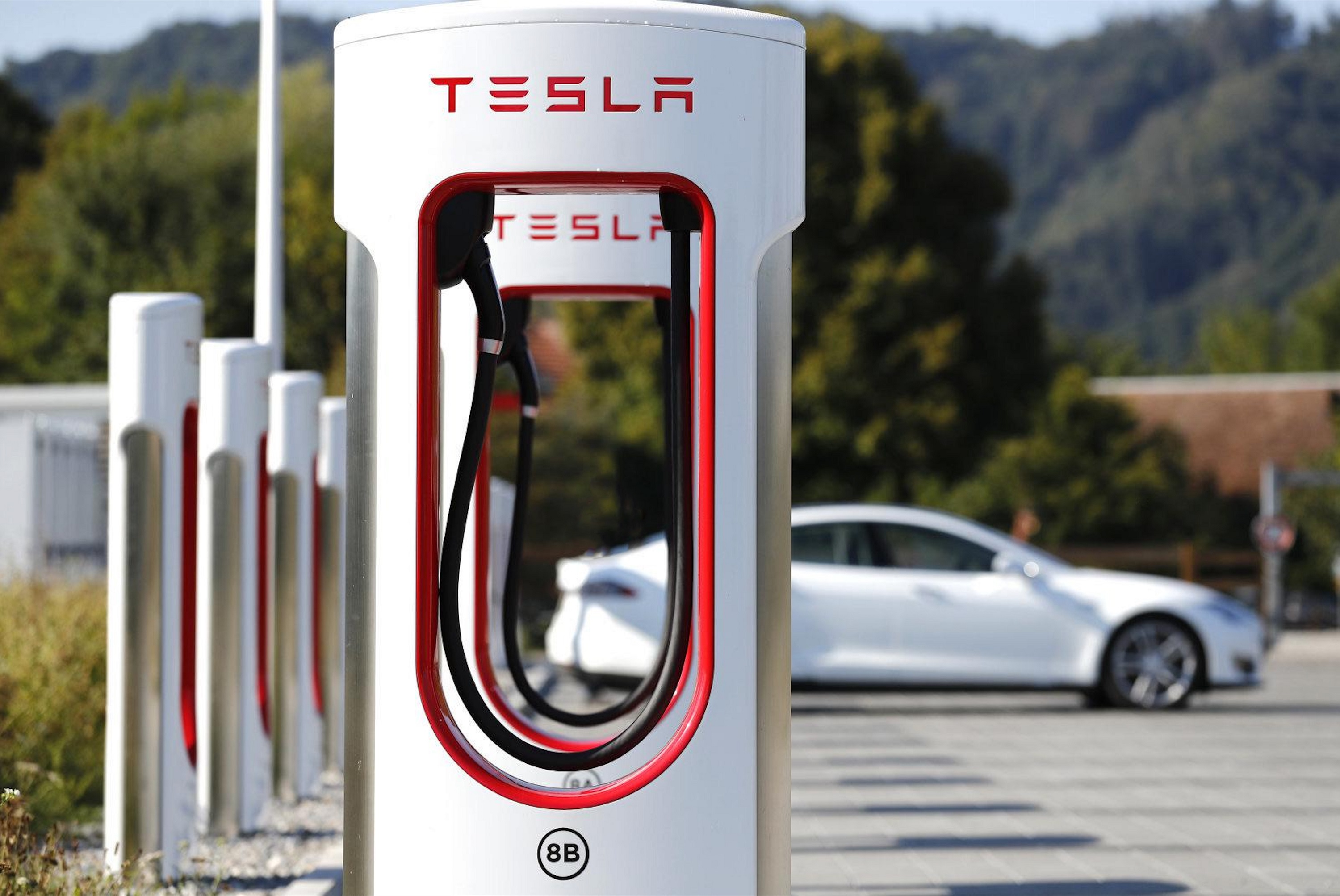 Photograph of a white Tesla model 3 charging through the supercharger.