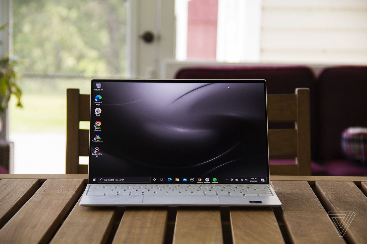 The Dell XPS 13 OLED open on a table. The screen displays a black background.