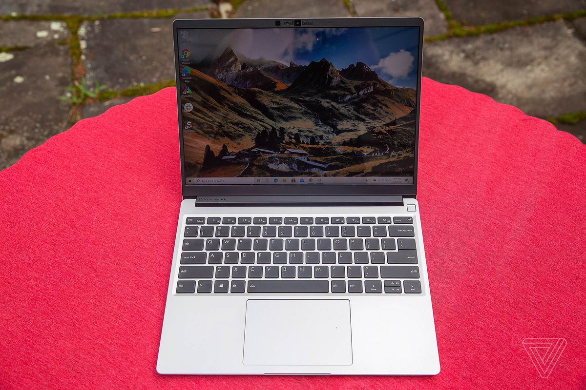 The Framework Laptop outdoors on a red tablecloth, seen from above, open. The screen displays a mountainous landscape.