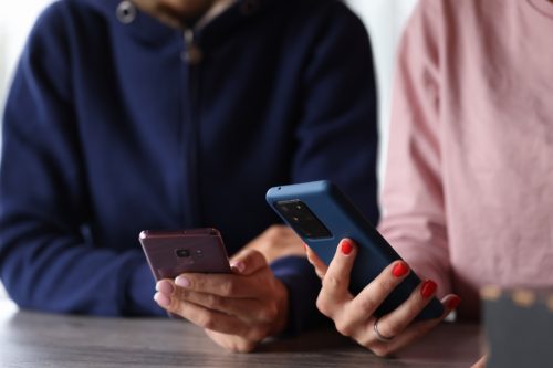 Two women are holding smartphones in their hands. Smartphone remote applications concept