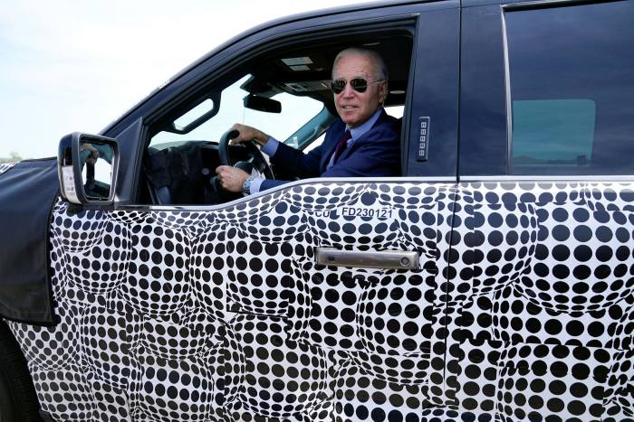 President Joe Biden stops to talk to the media as he drives a Ford F-150 Lightning at a Michigan test site