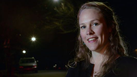 Maggie Ullman, former city sustainability officer, stands in front of a row of LED street lights on South French Broad Avenue. Installation of the lights cut carbon emissions and electricity costs in the city.